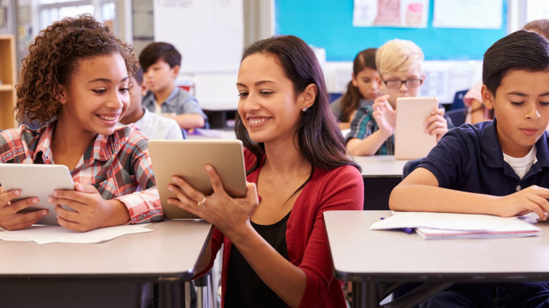 Teacher helping kids with computers in elementary school